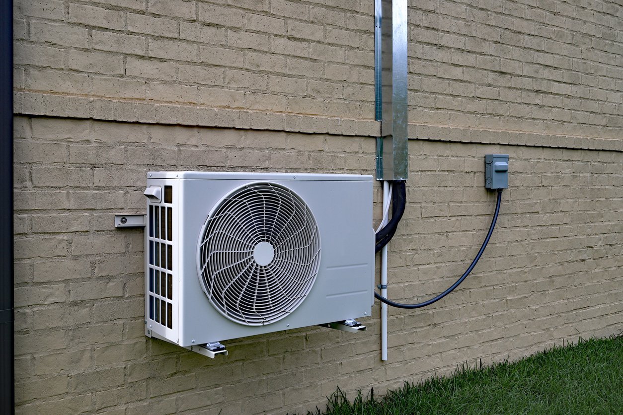 Technician performing seasonal HVAC tune-up at residential system in garage